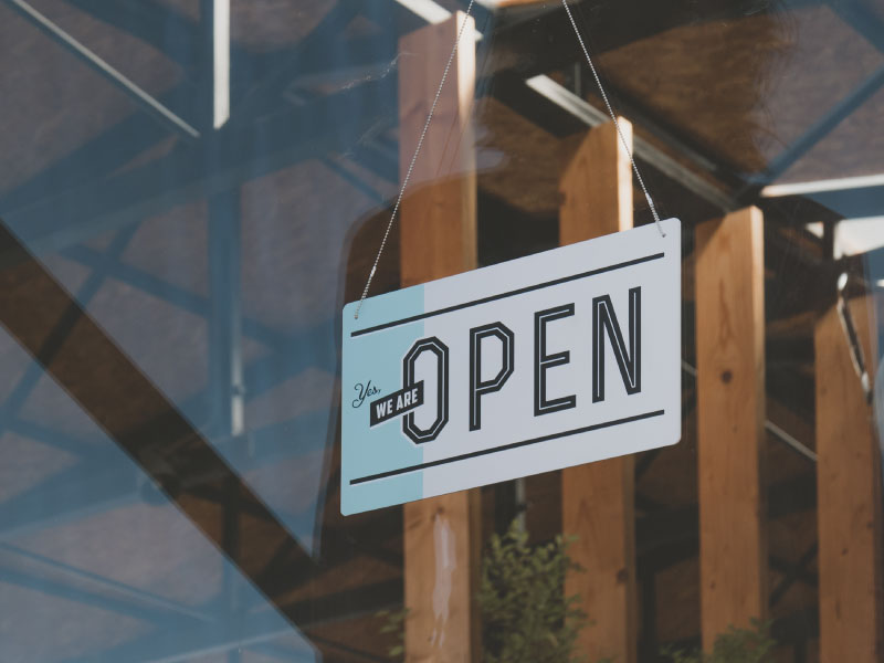 open sign hanging in front glass of store