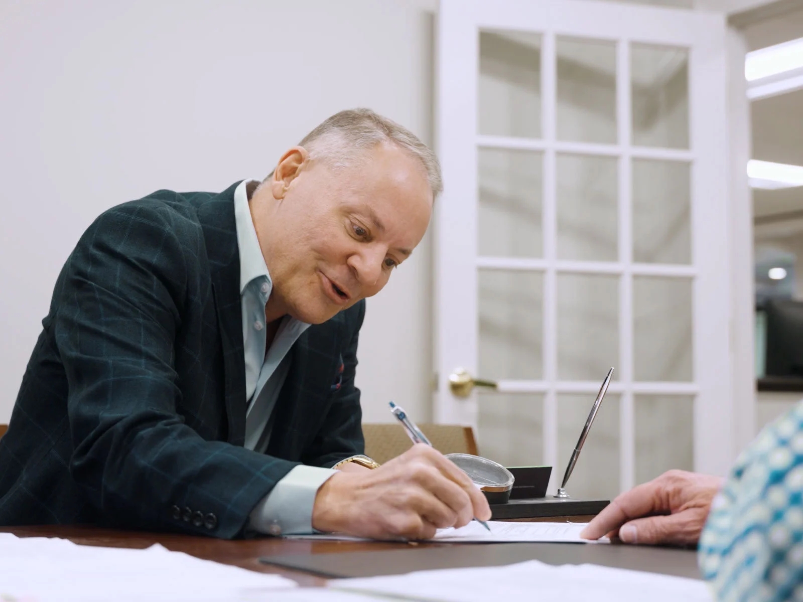 dr robert zoellner holding a pen signing documents inside of an office setting